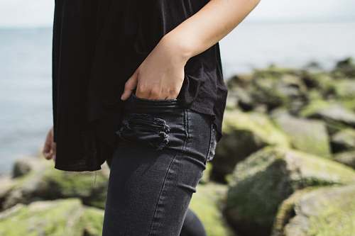 hand in pocket person wearing black denim bottoms near on body of water during daytime jeans